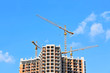 © Unkas Photo - Crane and building construction site against blue sky