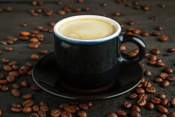 Cup of coffee and coffee beans on wood closeup