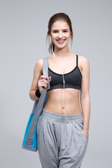 Poster - Happy fit woman standing with yoga mat over gray background