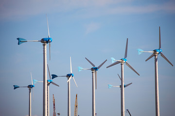 Green renewable energy concept - wind generator turbines on blue