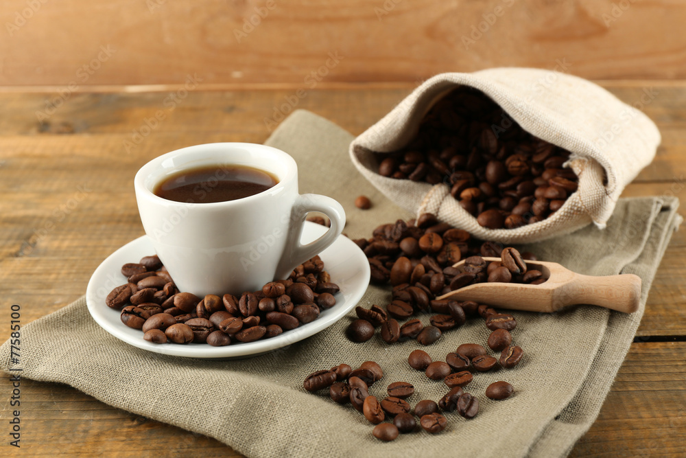 Cup of coffee with beans on rustic wooden background