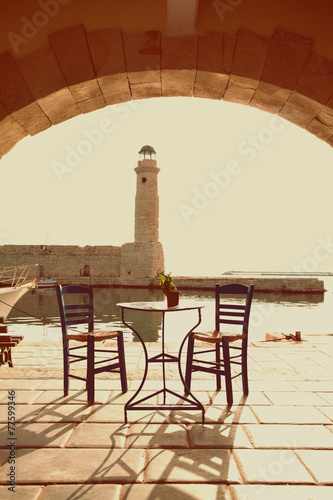 Fototapeta na wymiar Old vintage cafe and lighthouse on the sea Rethymnon Crete, imp