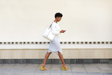 Young Woman Walking And Sending Text Message On Cell Phone