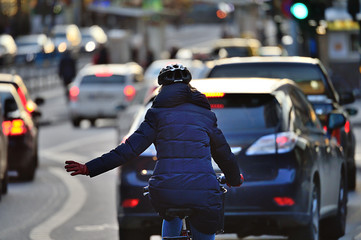 Winter city scene. Woman on bike in traffic