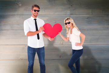 Poster - Composite image of cool young couple holding red heart