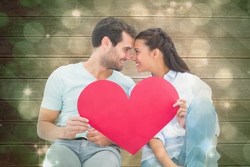 Aufkleber - Composite image of cute couple sitting holding red heart