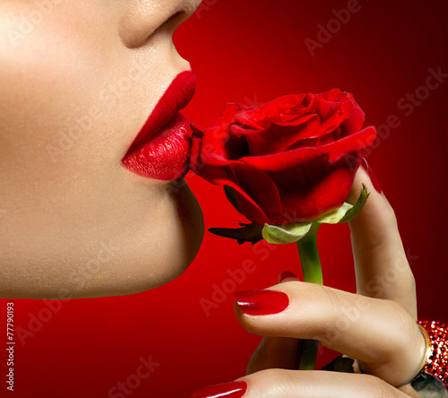 Nowoczesny obraz na płótnie Beautiful model woman kissing red rose flower. Sexy red lips