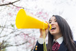 © Ni_photo - 桜をバックにメガホンで応援をする女子学生