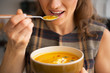© Alliance - Closeup on young woman eating pumpkin soup in kitchen