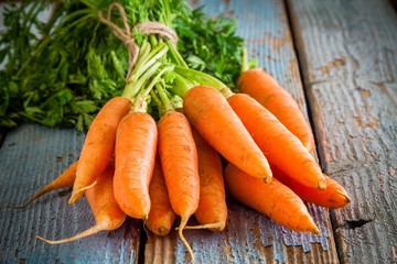 Wall Mural - fresh carrots bunch on wooden background