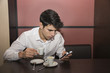 © theartofphoto - Young Man Drinking Coffee While Looking at Mobile Phone
