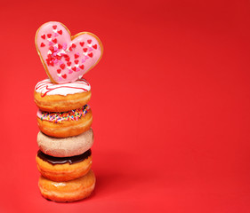 Wall Mural - Sweet donuts with heart shaped donut on the top over red