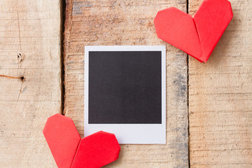 Instant photo with origami hearts. On wooden background