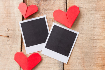 Instant photos with origami hearts. On wooden background