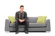 © Ljupco Smokovski - Cheerful young man sitting on a modern sofa