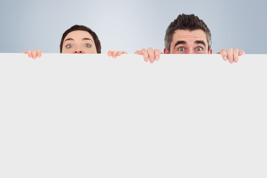 Man and woman hiding behind a white board