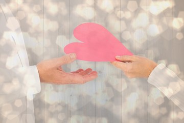 Poster - Composite image of woman handing man a paper heart