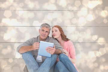 Poster - Composite image of casual couple sitting using tablet