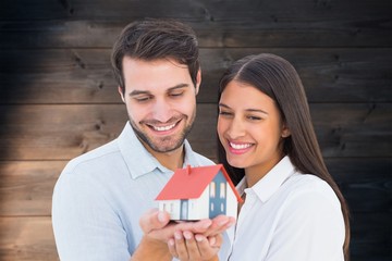 Poster - Composite image of attractive young couple holding a model house