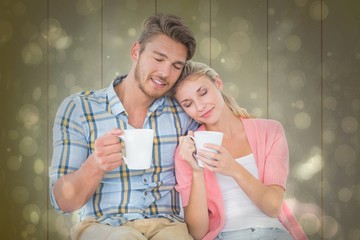 Poster - Composite image of attractive young couple sitting holding mugs