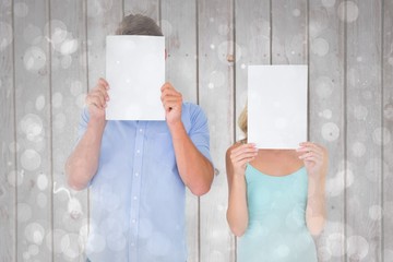 Poster - Composite image of young couple holding pages over their faces