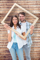 Poster - Composite image of happy young couple holding picture frame