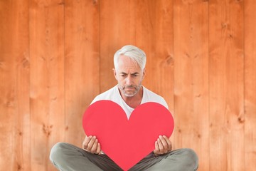 Poster - Composite image of upset man sitting holding heart shape