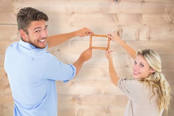 Poster - Composite image of attractive young couple hanging a frame