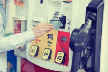 Woman hand swiping credit card at gas pump station