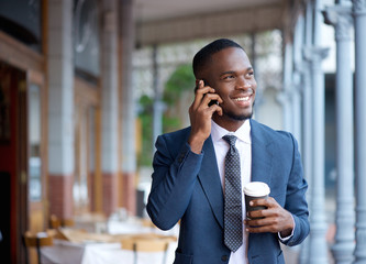 Smiling businessman walking and talking on mobile phone