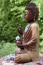 Wooden Buddha Statue In Garden With Flower