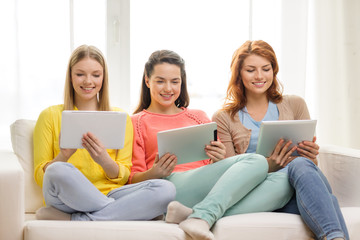 Wall Mural - three smiling teenage girls with tablet pc at home