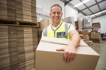 Worker carrying box in warehouse