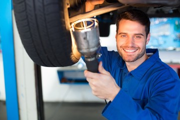 Poster - Mechanic using torch to look under car