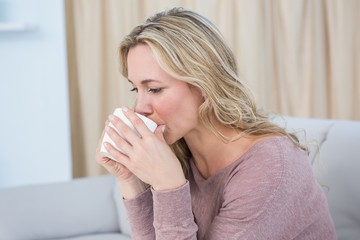 Wall Mural - Pretty blonde sitting on couch drinking coffee