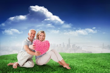 Aufkleber - Composite image of happy couple sitting and holding heart pillow