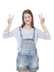 Young fashion girl in jeans overalls with horn gesture isolated