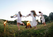 Girls in Ukrainian national shirts dancing around a campfire