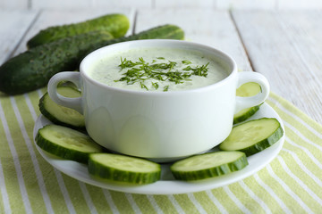 Wall Mural - Cucumber soup in bowl on color wooden table background