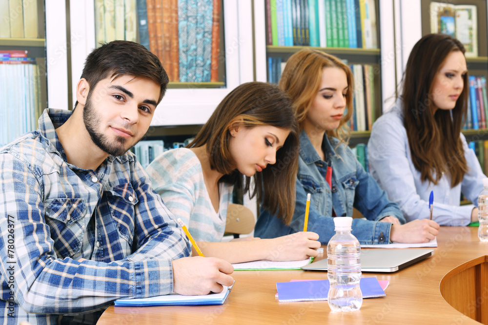Group of students sitting at table in library