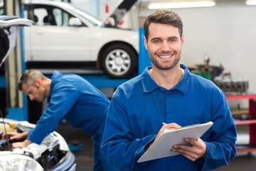 Poster - Smiling mechanic writing on clipboard