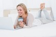 © WavebreakMediaMicro - Cheerful blonde shopping online on the bed