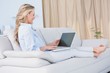 © WavebreakMediaMicro - Smiling blonde relaxing on couch with her laptop