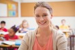 © WavebreakMediaMicro - Pretty teacher smiling at camera at top of classroom
