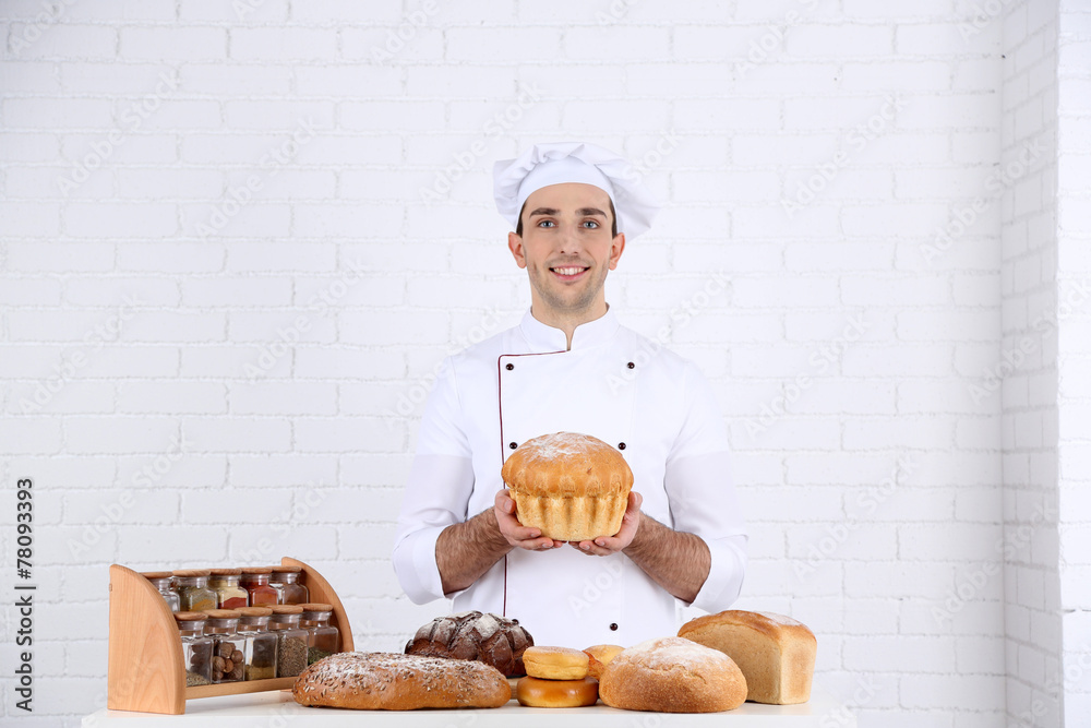 Baker in kitchen at table with freshly loaves of bread