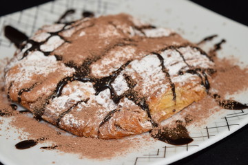 Wall Mural - Croissant with powder sugar and melted chocolate on it.