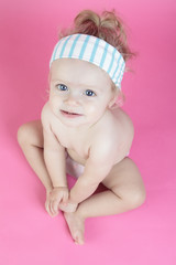 A happy baby girl isolated on pink background