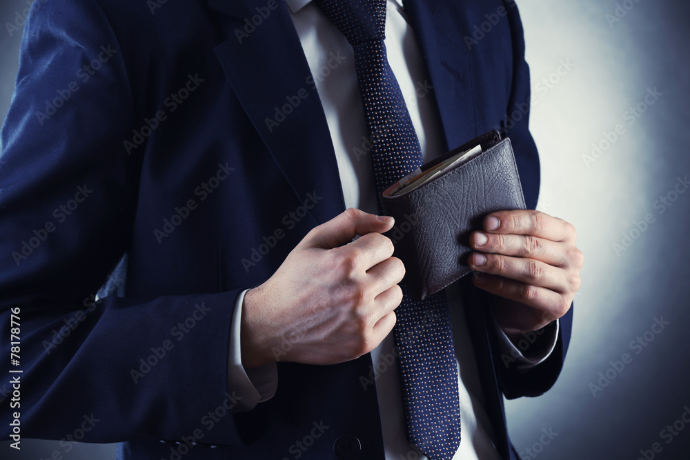 Leather wallet with money in male hands on dark background