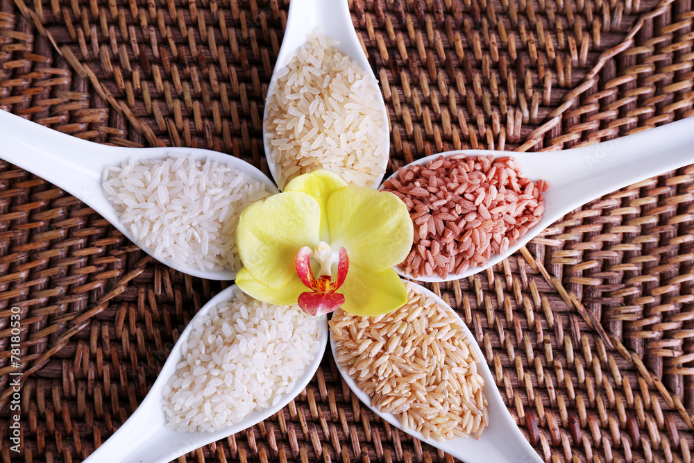 Different types of rice in spoons on wicker background