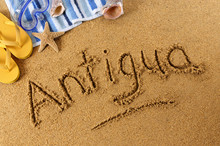 The Word Antigua Written In Sand On A Beach With Towel Flip Flops Seashells Summer Vacation Holiday Photo